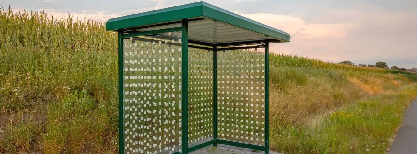 Groene overkapping met glazen zijwanden voor bushalte en betaalautomaat