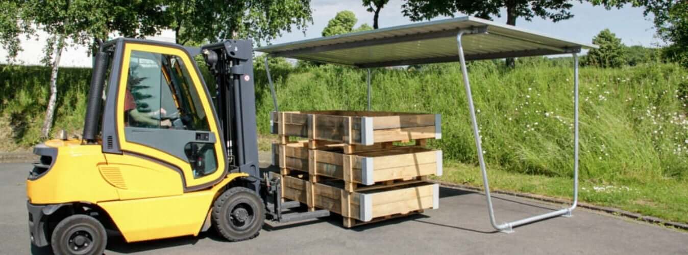 Materiaaloverkapping voor buitenopslag van goederen, verzinkt staal en bouwpakket. Op de afbeelding is een heftruck te zien die een pallet plaatst.