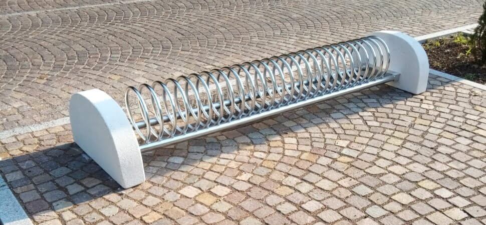 RVS fietsenrek met betonvoeten geplaatst op tegels op een stoep.