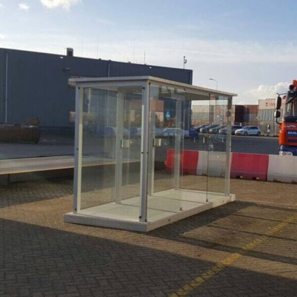 Mobiele rookoverkapping op betonplaat kopen Transparante rookoverkapping van glas en metaal op een prefab betonplaat, geplaatst op een industrieterrein