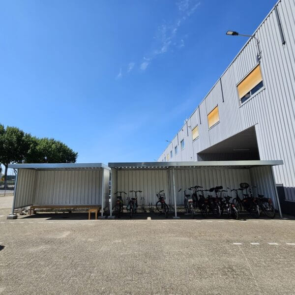 Fietsenberging bouwpakket kopen Fietsenberging als bouwpakket met zij- en achterwand, geplaatst bij een bedrijfspand.