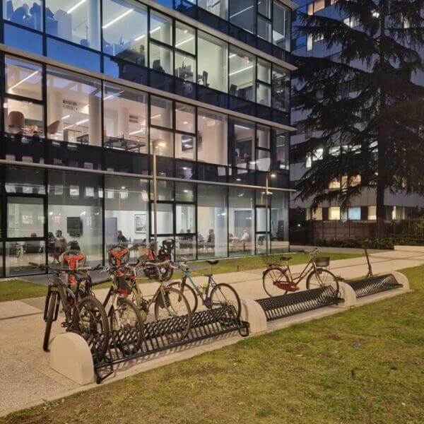 Fietsenrek dubbelzijdig in RAL-kleur kopen Dubbelzijdig fietsenrek van staal en met betonvoet in RAL-kleur met fietsen voor een kantoorgebouw