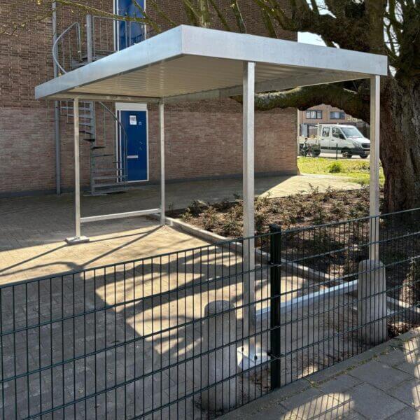Fietsoverkapping klein kopen Kleine fietsenstalling van verzinkt staal naast schoolgebouw met boom