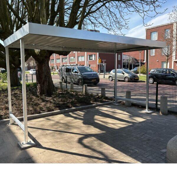 Overdekte fietsenstalling aanschaffen Overdekte fietsenstalling van verzinkt staal bij school met vlak dak