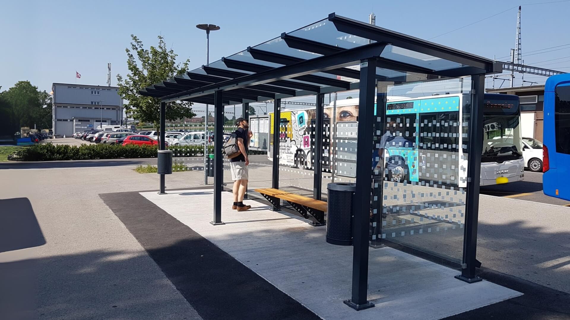 Bushokje met zitbank, prullenbak en glazen wanden bij busstation