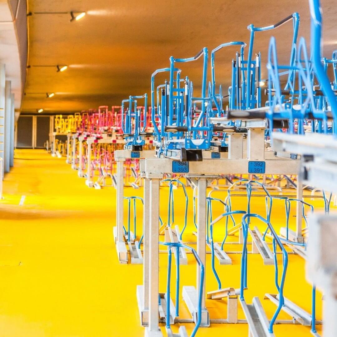 Dubbellaags fietsenrek met blauwe en roze fietsklemmen in fietsenstalling