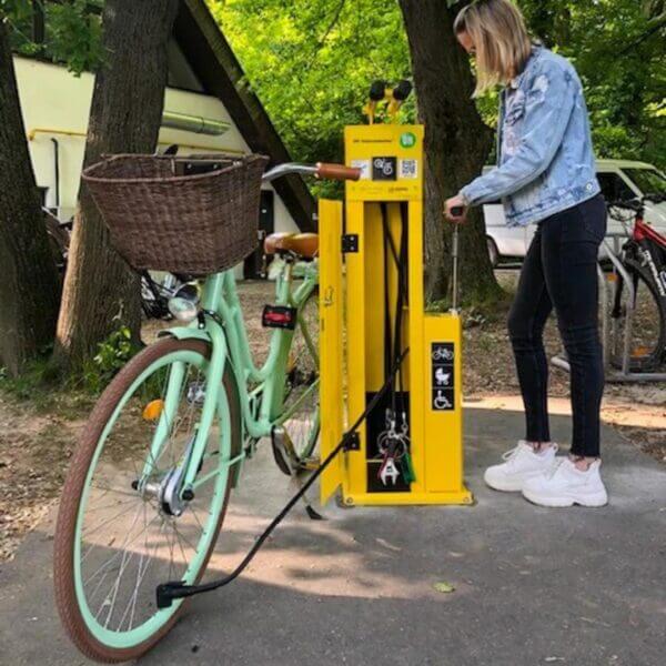 fiets-onderhoudsstation-umfeldt-scandic-met-deur-27 Gele fiets onderhoudsunit in gebruik door vrouw met mintgroene fiets