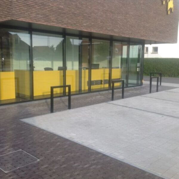 fietsnietje-zwart-direct-online-voor-fietsen-kopen Zwarte fietsnietjes gemonteerd in beton voor een glazen gevel