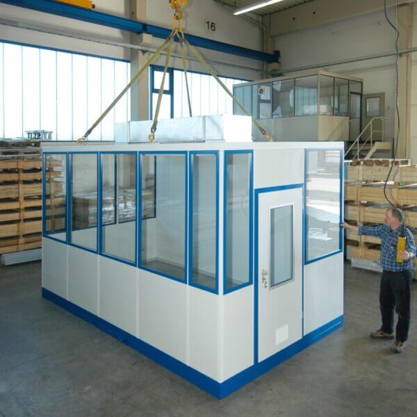 Verplaatsbare kantoorunit bestellen Verplaatsbare kantoorunit wordt omhoog getild voor installatie in een industriële werkruimte.