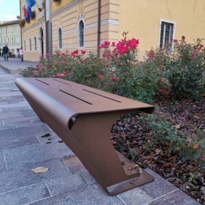 Cortenstalen parkbank zonder rugleuning naast rozenperk en gemeentehuis