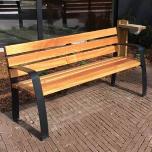 Houten seniorenbank met zwart stalen frame op een ondergrond van straatklinkers.