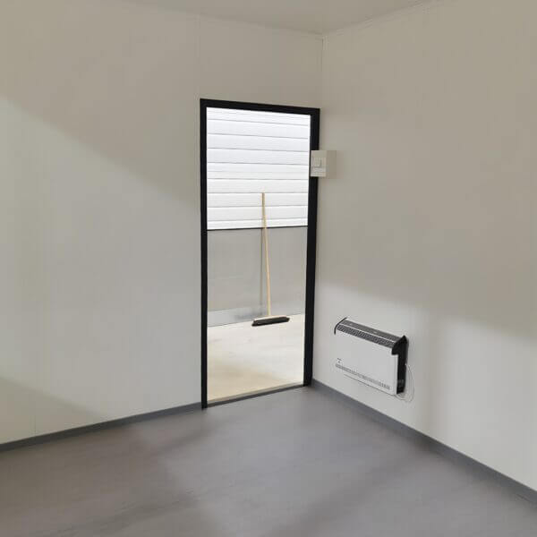 Prefab Kantoorunit Met Kachel Kopen Prefab kantoorunit met open deur en rechts een kachel.