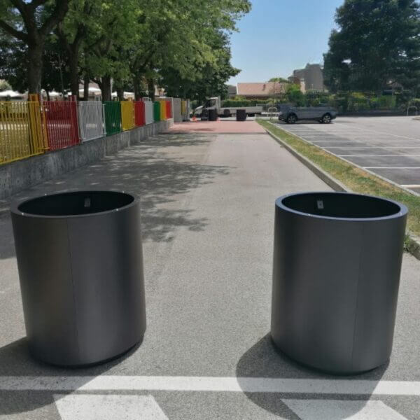 ronde-plantenbak-voor-buiten-kopen Ronde stalen plantenbak in antracietkleur, geplaatst op een verharde ondergrond in de openbare ruimte