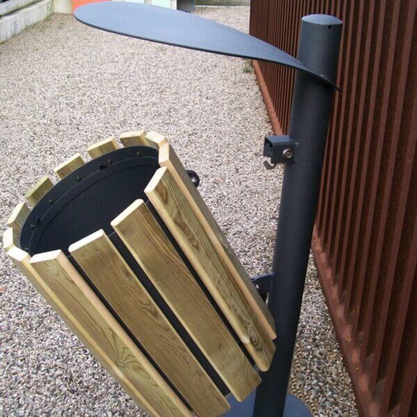 vuilnisbak voor buiten hout bestellen Buitenprullenbak met houten latten en zwart stalen frame, voorzien van afdak en verankerd op grindondergrond