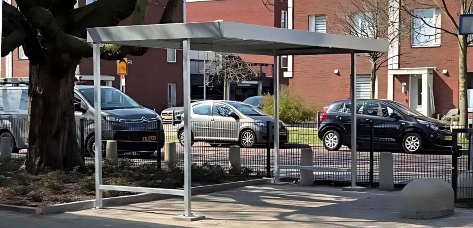 Fietsoverkapping met stalen frame en plat dak, geplaatst bij een school in Brabant, geleverd door Umfeldt voor medewerkers en bezoekers.