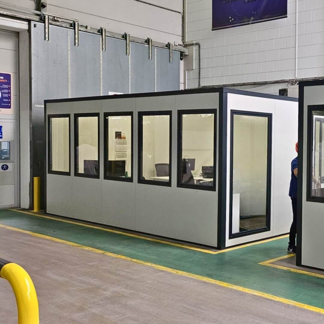 Mobiele kantoorunit met ramen, geplaatst in een productiehal voor afgeschermd en flexibel werken