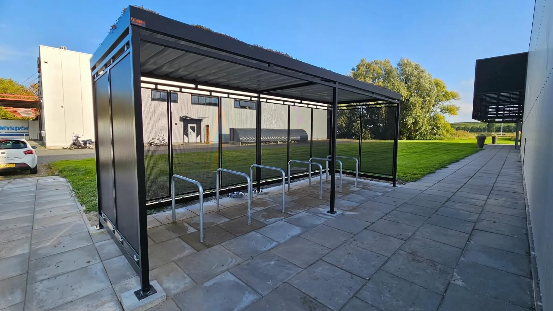 Fietsoverkapping met meerdere fietsaanleunbeugels voor veilige en overdekte stalling bij een bedrijfsgebouw.