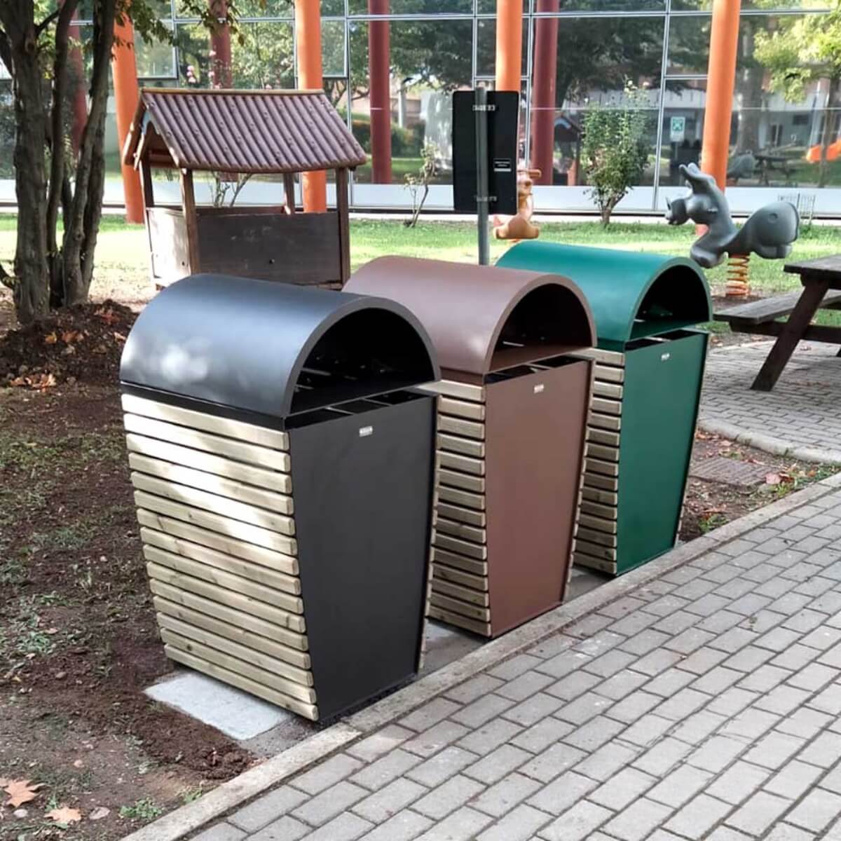 3 stalen straatmeubilair afvalbakken voor buiten in 3 verschillende kleuren, geplaatst bij een speeltuin