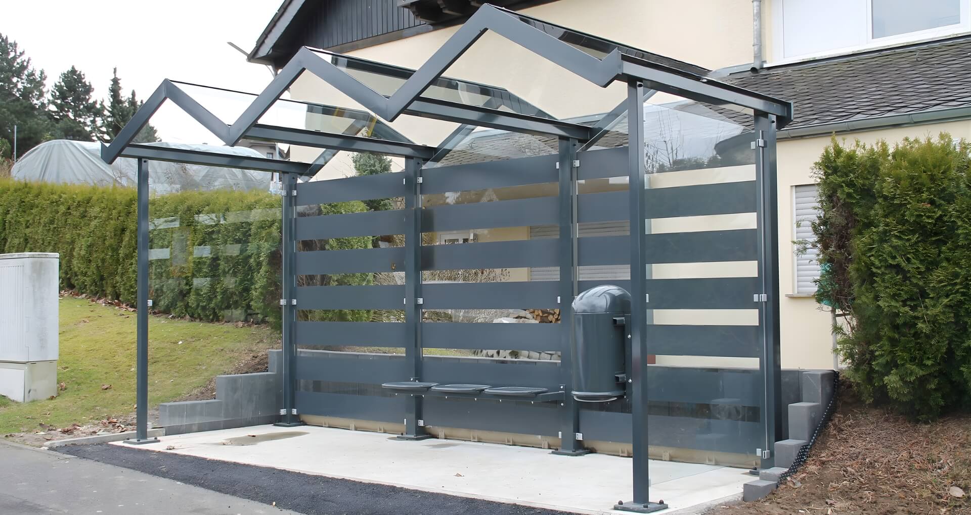 Moderne rookoverkapping met donker stalen frame en half transparante panelen bij een gebouw
